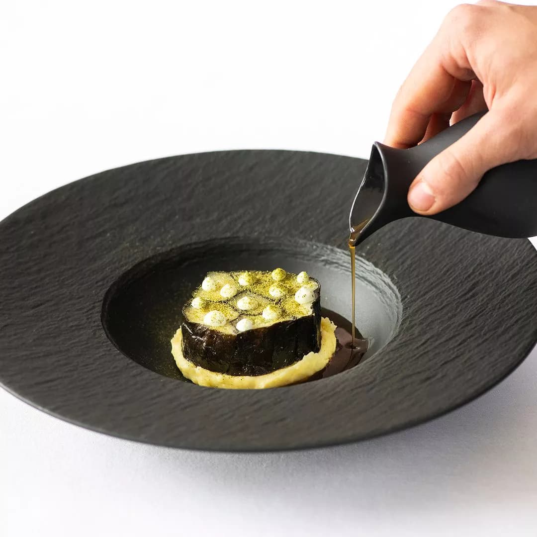 Sissi — Seasonal vegetable composition on dark slate, sauce poured tableside
