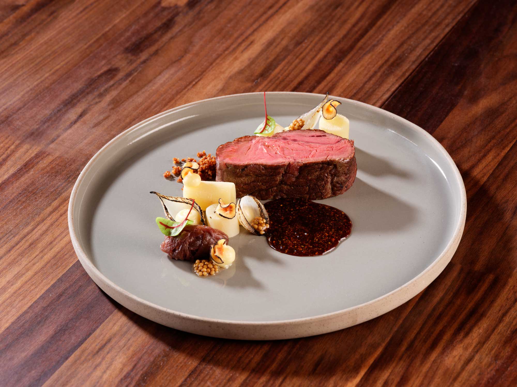 Stuba Adelboden — Beef fillet with dark sauce on grey ceramic plate, Chef Björn Inniger