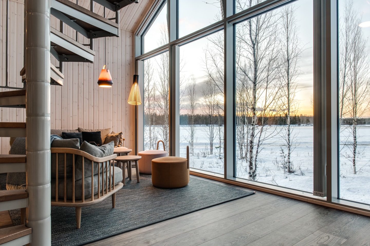 Arctic Bath — Wohnbereich einer Kabine mit raumhohen Fenstern und Wendeltreppe