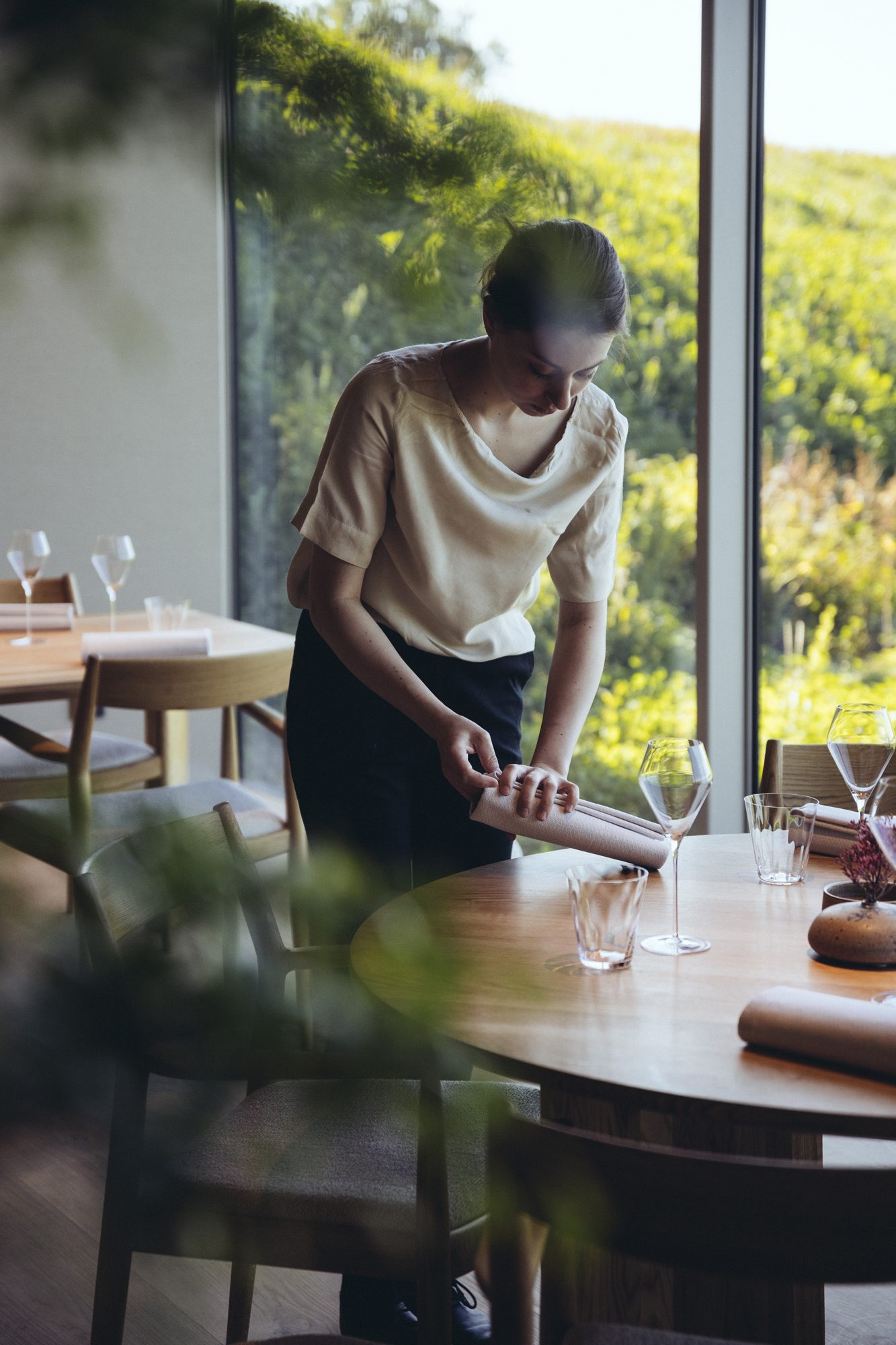 Restaurang ÄNG, Ästad Vingård — Service am Tisch vor der Glasfront mit Blick auf die Hügel