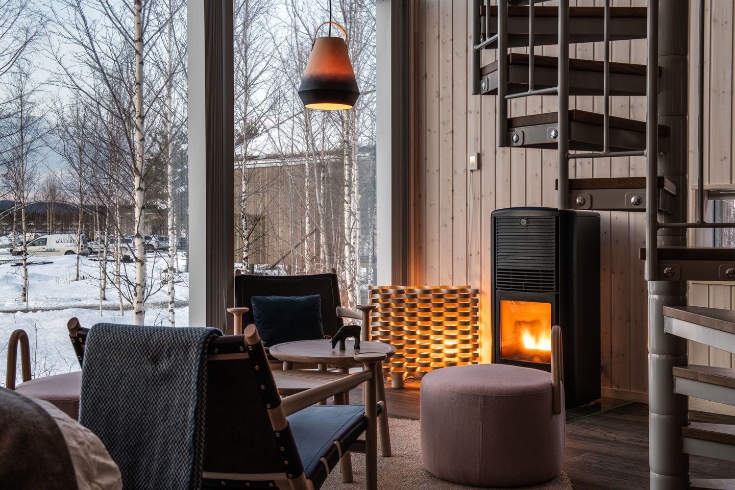 Arctic Bath — Landkabine mit Kaminofen, Sesseln und Blick in die Winterlandschaft