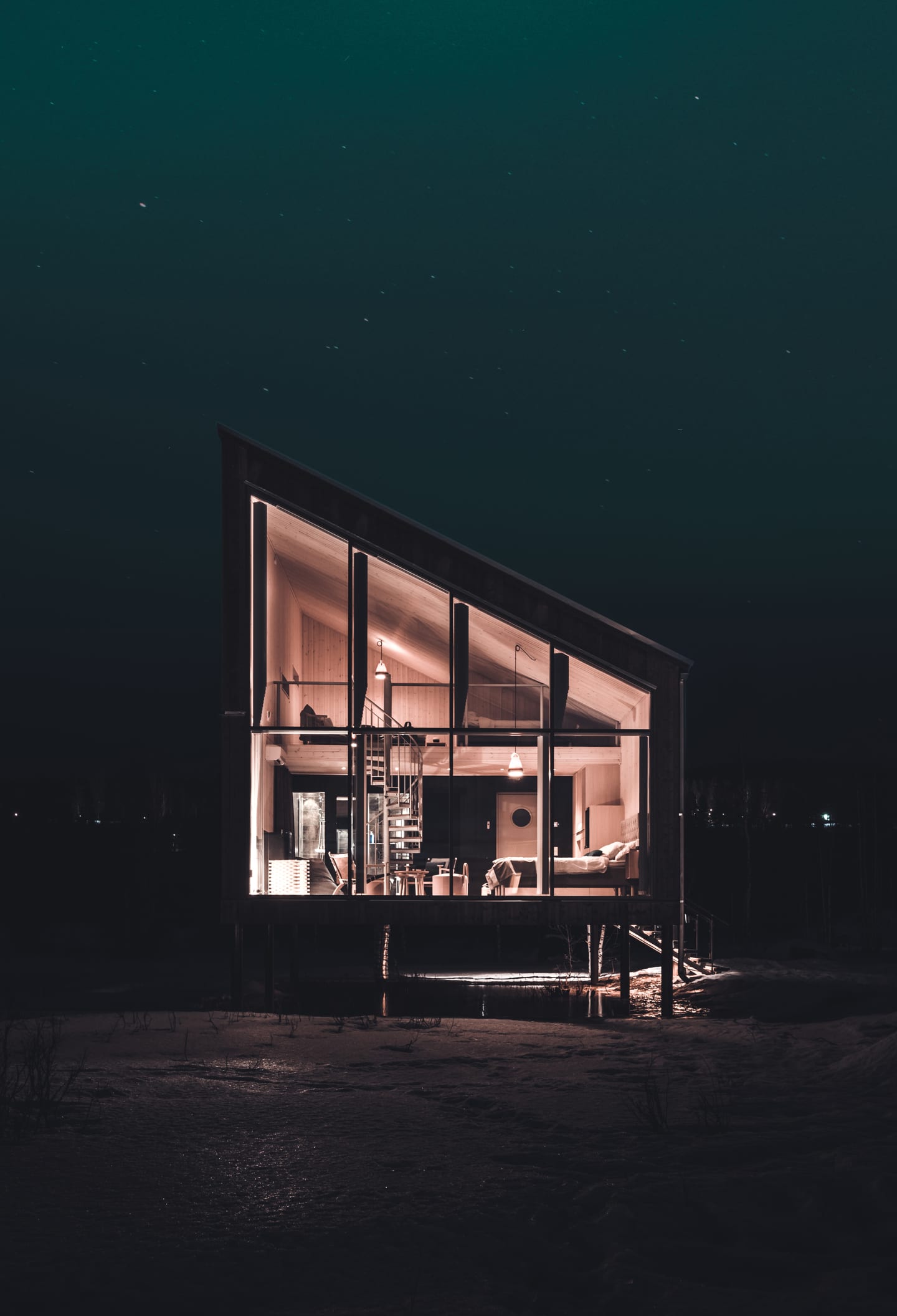 Arctic Bath — beleuchtete Cabin mit großen Fenstern in der winterlichen Dunkelheit