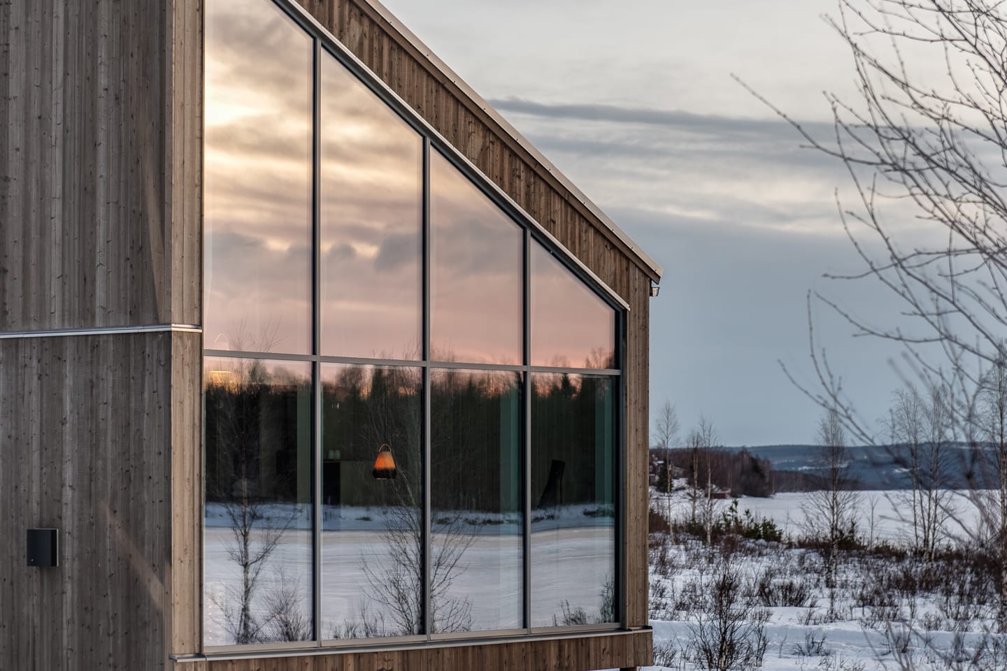 Arctic Bath — Land-Cabin mit großen Fensterflächen im Schnee bei Sonnenuntergang
