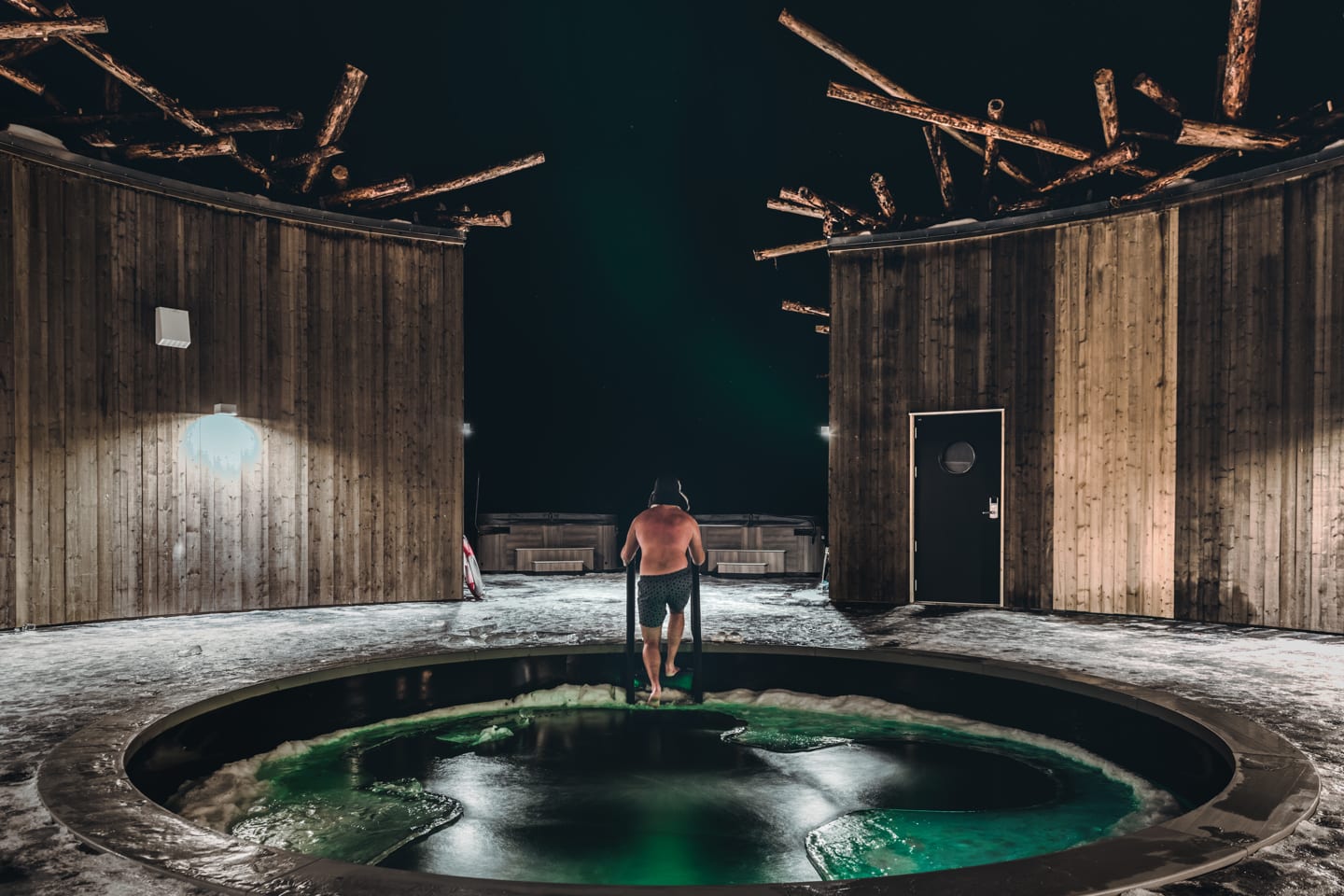 Arctic Bath — Gast im kalten Wasser des zentralen Eisbads unter dem nächtlichen Himmel