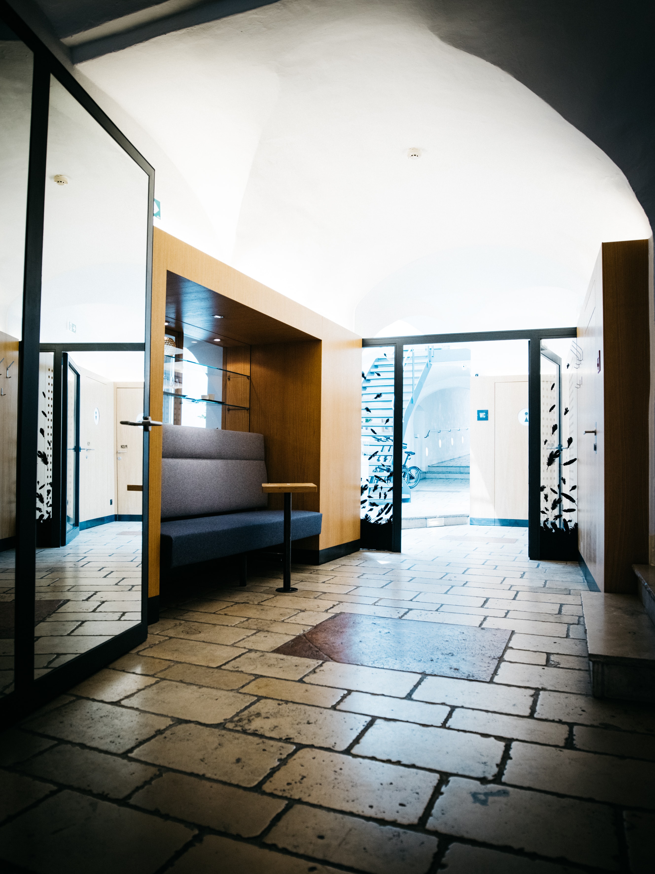 Arthotel Blaue Gans — Empfangsbereich mit altem Steinboden, Gewölbe und moderner Holzsitzbank