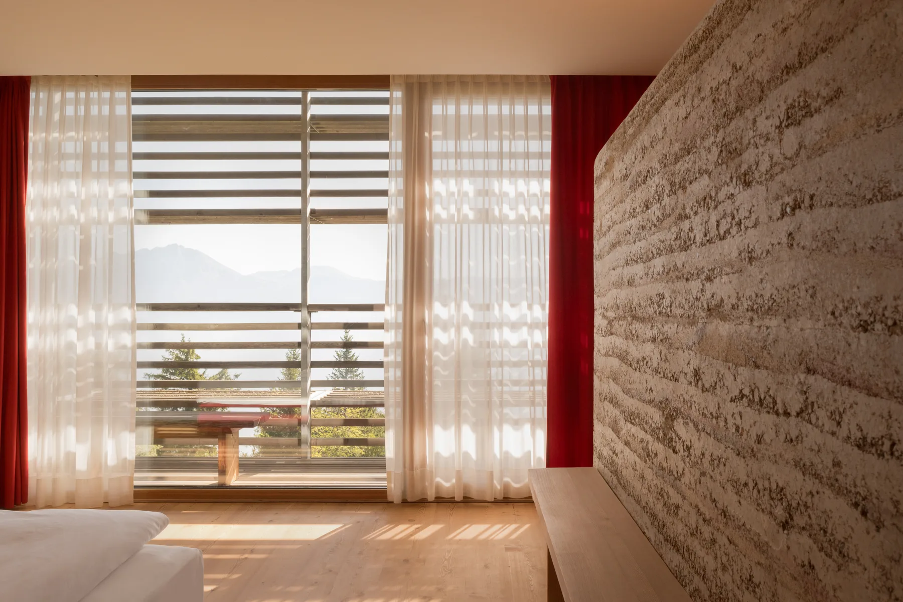 Guest room with clay wall, larch floor and mountain view at vigilius mountain resort.