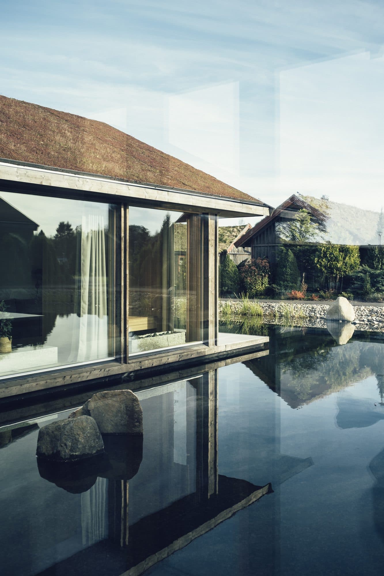 Ästad Vingård — die Sjöparken-Pavillons spiegeln sich im stillen Naturpool im Zentrum des Weinguts
