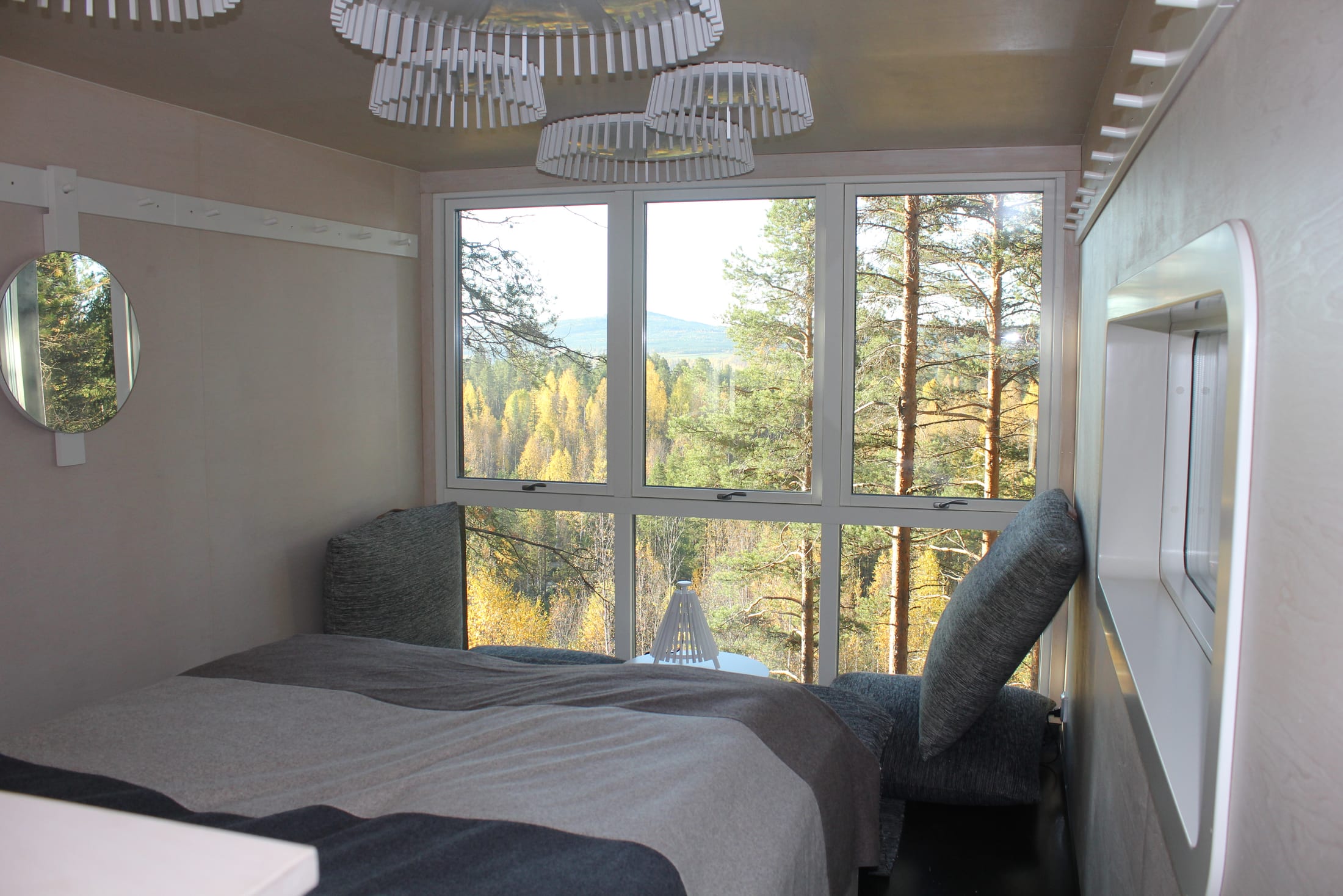 Treehotel — Innenraum von The Cabin mit panoramischer Fensterfront zum Wald