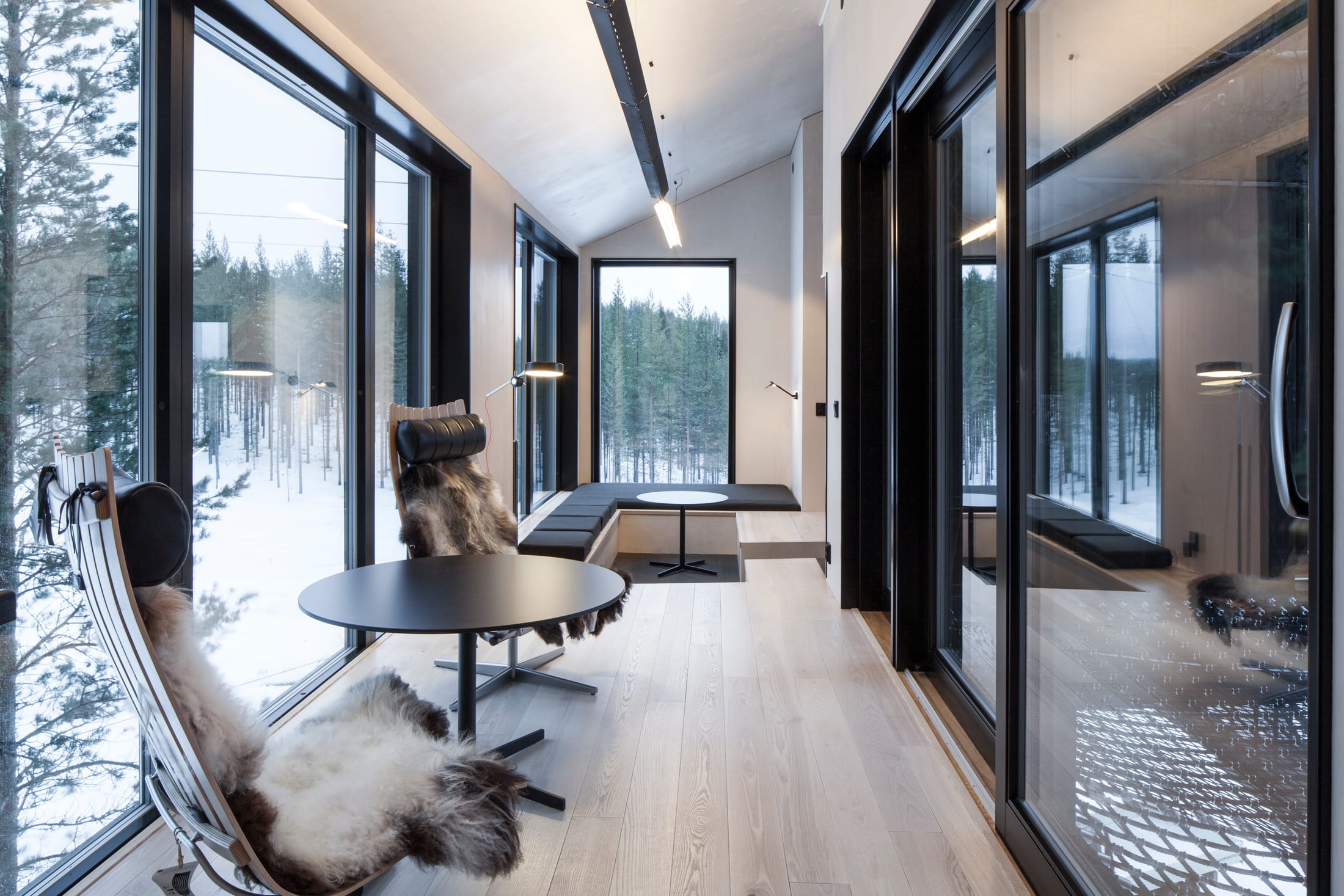 Treehotel — Innenraum des 7th Room mit großen Fenstern und Blick in die Baumkronen