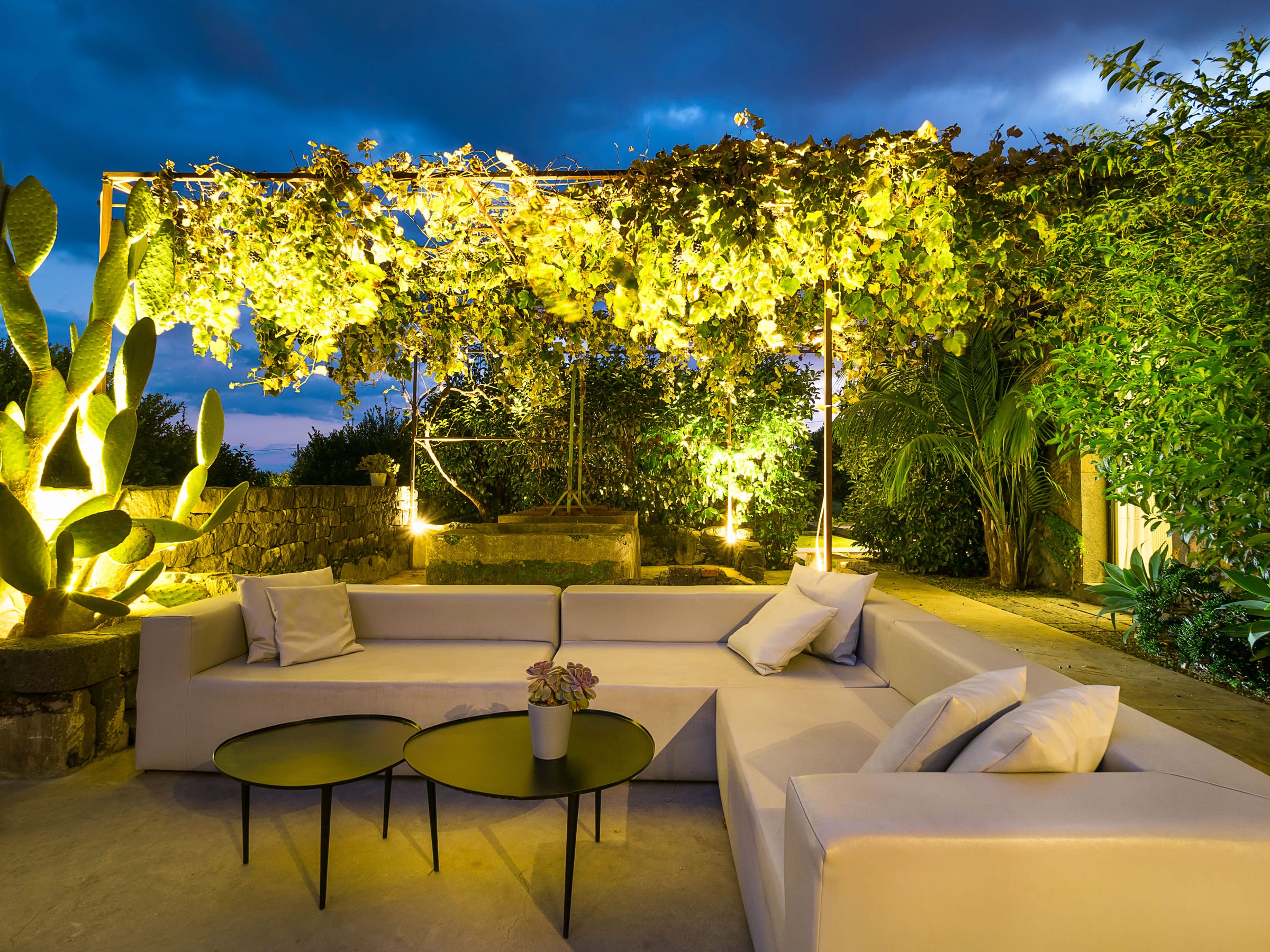 ZASH — Gartenlounge unter Rankpflanzen, abendlich beleuchtet